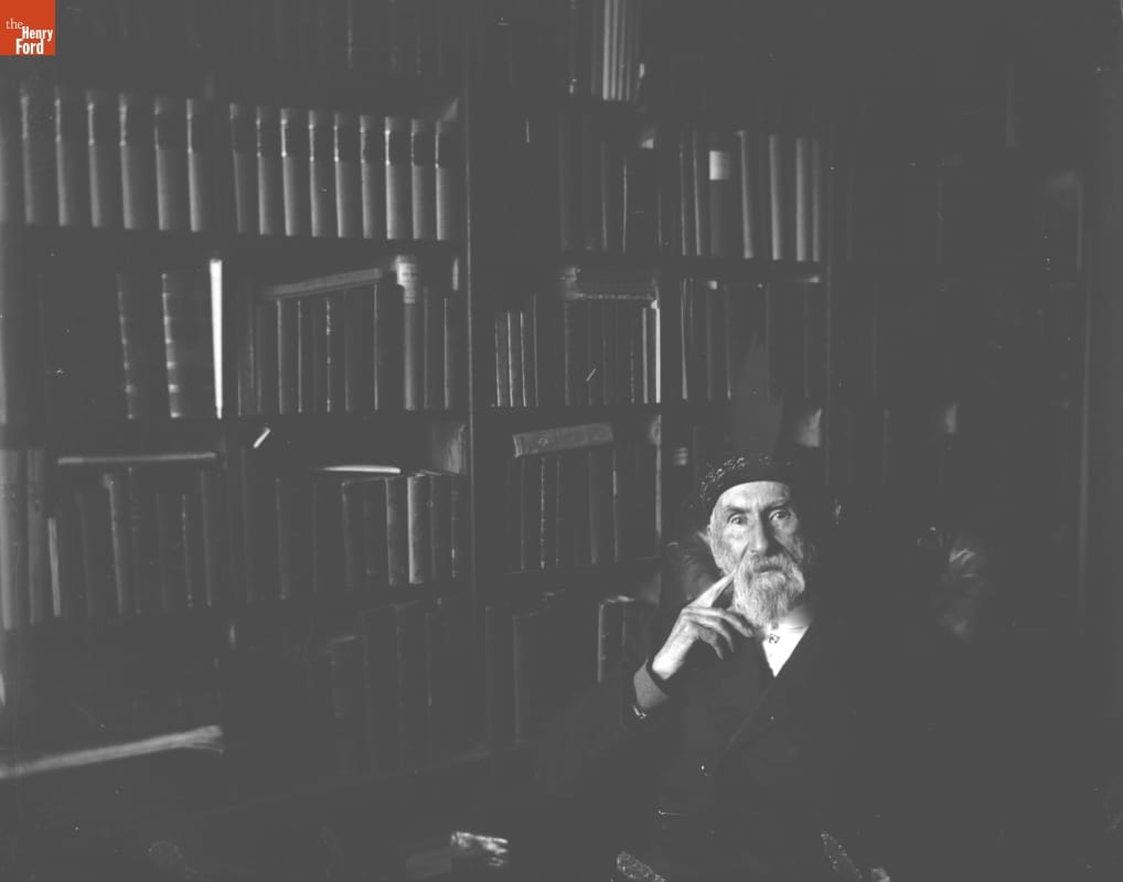 Man sitting in front of wall filled with books