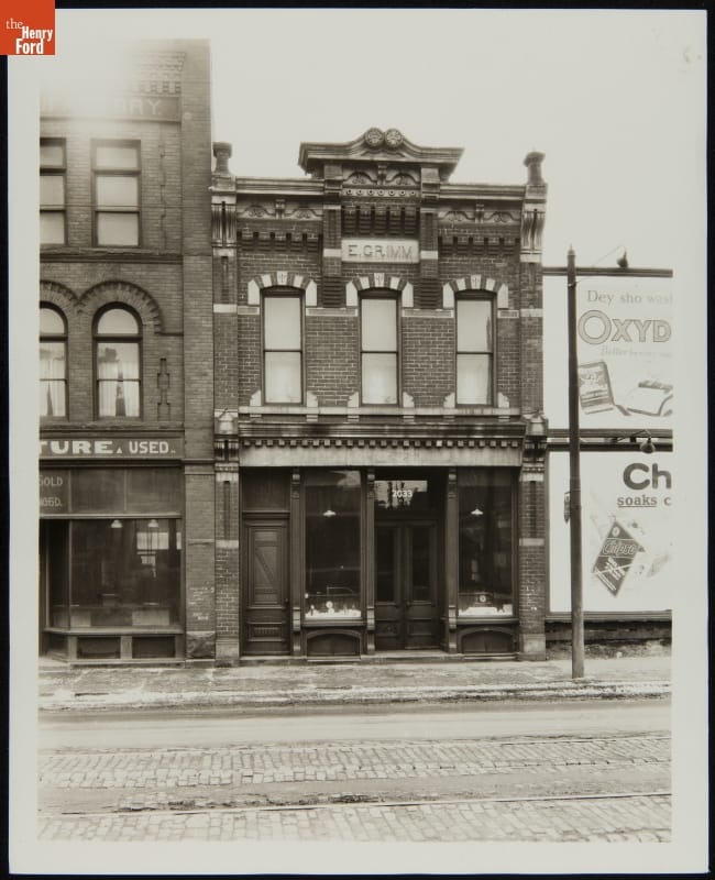 Grimm Jewelry Store on Its Original Site, 1926 Black-and-white photograph of two-story brick building with decorative windows and cornice
