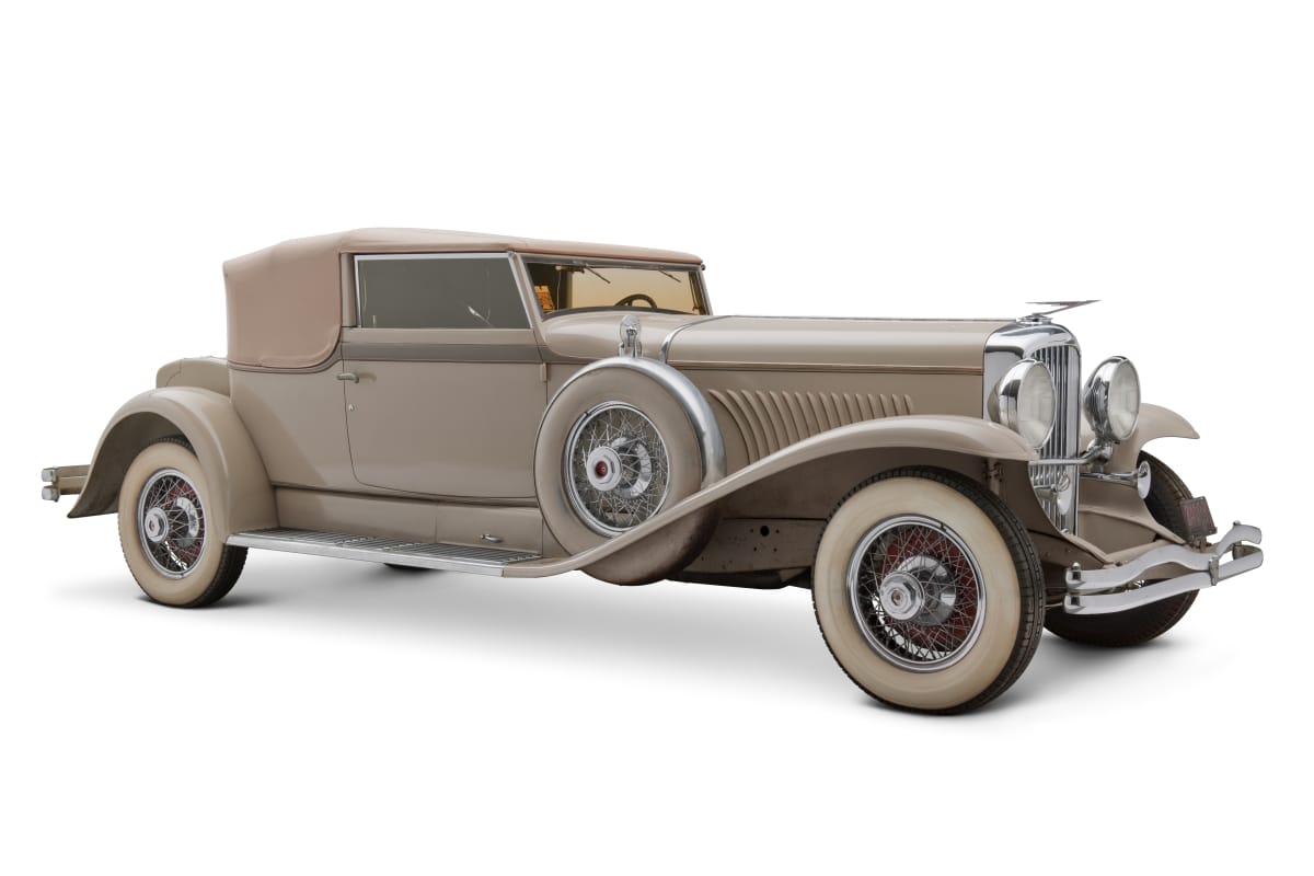 1931 Duesenberg Model J Convertible Victoria Long beige car with swooping fenders and color-matching tires