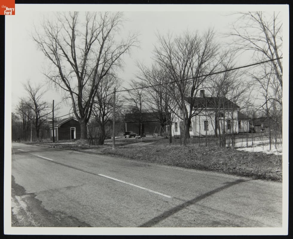 Dr. Howard's Office at Its Original Site, Tekonsha, Michigan, March 1956 Several buildings visible within a group of trees at the side of a road