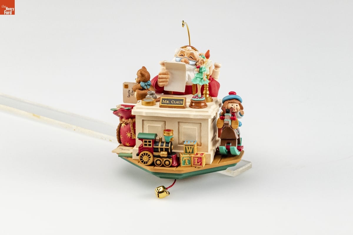 Hallmark "Letters to Santa" Christmas Ornament, 2006 Ornament depicting Santa Claus sitting behind a desk with sign "Mr. Claus," looking at a piece of paper, with many toys on and around the desk