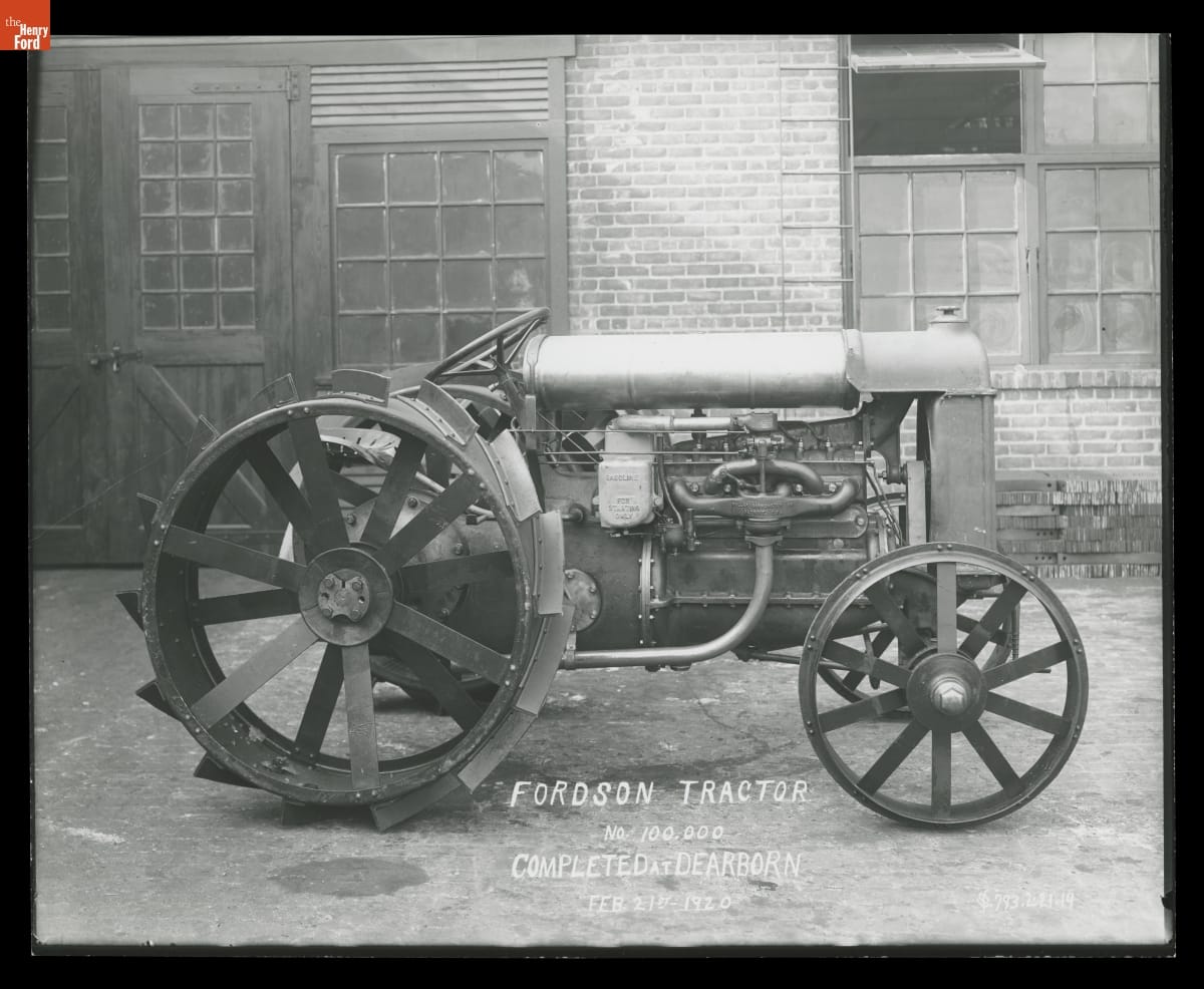 Fordson Tractor No. 100,000, Completed at Dearborn, February 21, 1920 Black-and-white photo of a tractor sitting in front of a brick building with wooden doors and windows; also contains text