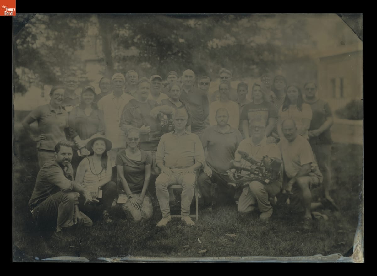 Film Crew of The Henry Ford's Innovation Nation in Greenfield Village, September 2019 Hard-to-see black-and-white image of a group of people posed for the photo on a lawn among trees