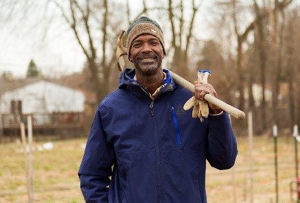 Melvin Parson Gardening during the Entrepreneurship Interview Smiling African American man in blue jacket and knit hat holding shovel on shoulder