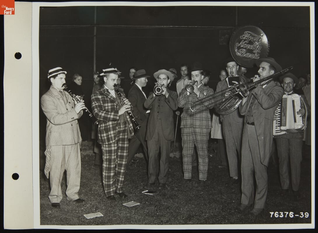 Ford Novelty Band Playing at Ford Baseball Team Game, 1941 Group of seven men in suits play instruments on a field with people in the background