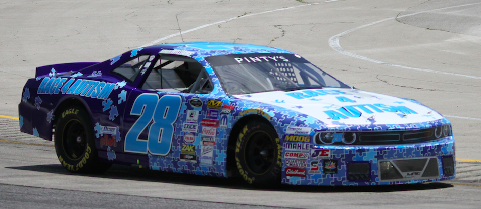 Race 4 Autism car driven by Armani Williams. Race car in dark and light blue with a pattern of puzzle pieces, much text, and many logos