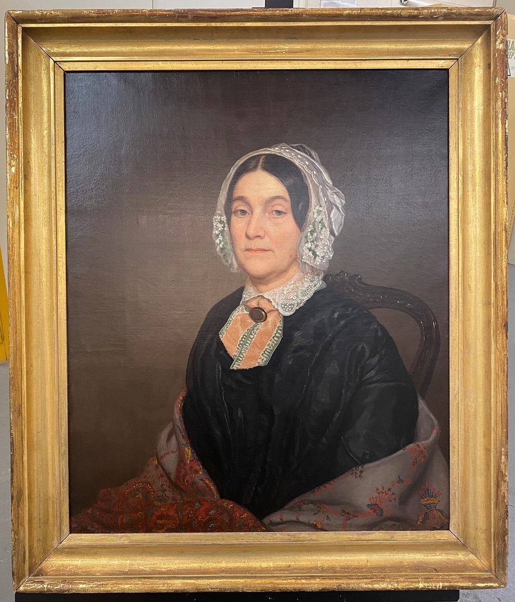 “Lady in a Lace Bonnet,” after conservation treatment Gold-framed painting of woman in black dress, shawl, and white lace bonnet