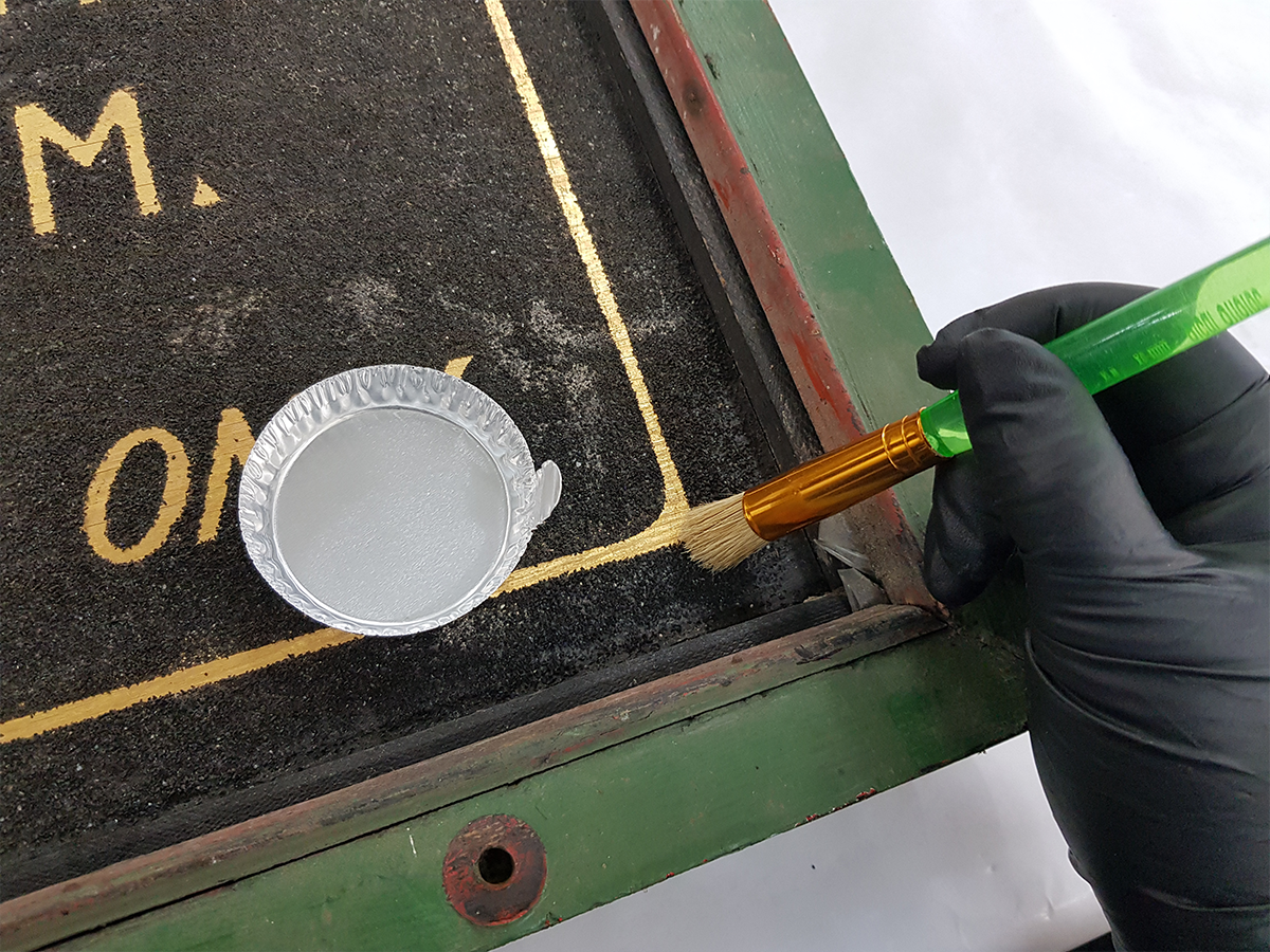 Surface cleaning of advertising artifact for Dr. W.E Coomer Dog and Cat Hospital, circa 1920. Dr. Ward E. Coomer.