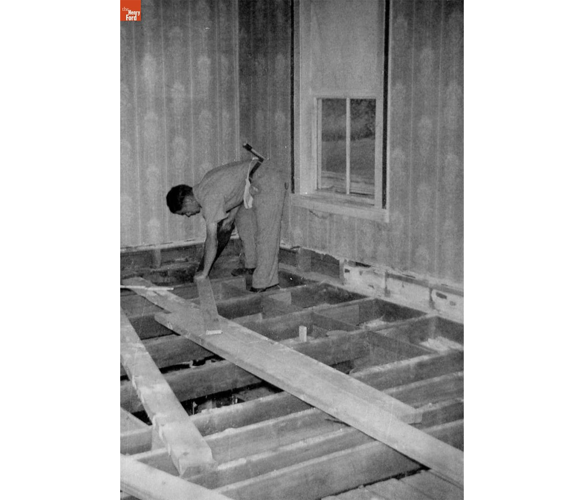 Charlie Magdefrau replacing floor joists in the Kelley house living room, Rockville, Connecticut, 1949. / THF723664