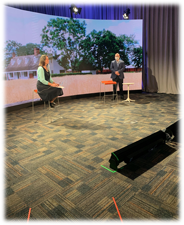 Curator of Agriculture and the Environment Debra Reid and Vice-President and Chief Advancement Officer Spence Medford Woman seated and man standing in front of a curved screen or backdrop